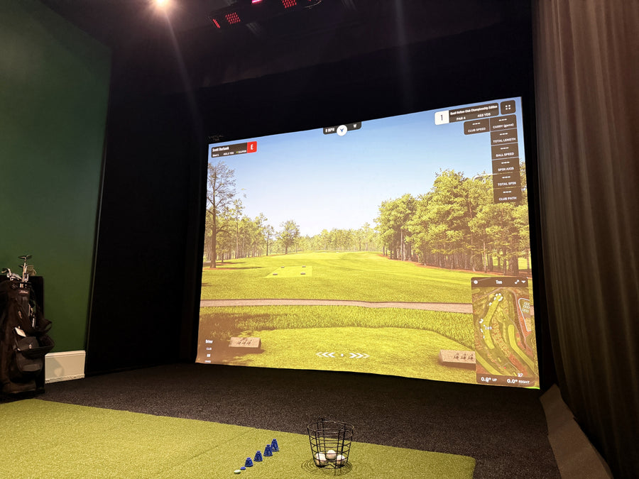 Indoor golf simulator setup with a screen displaying a golf course.