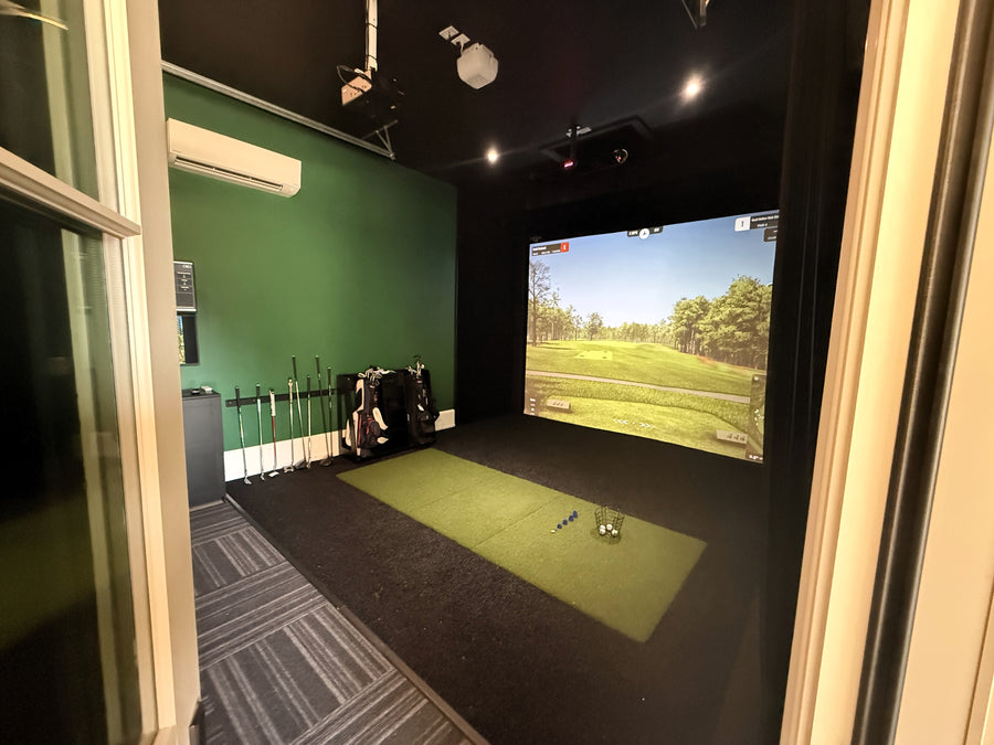 Indoor golf simulator setup with a screen displaying a golf course.