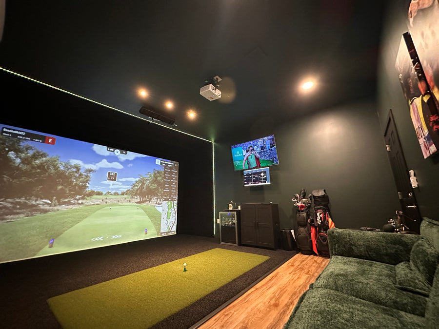 golf simulator with large screen displaying a golf simulation game, multiple televisions, and gaming equipment.