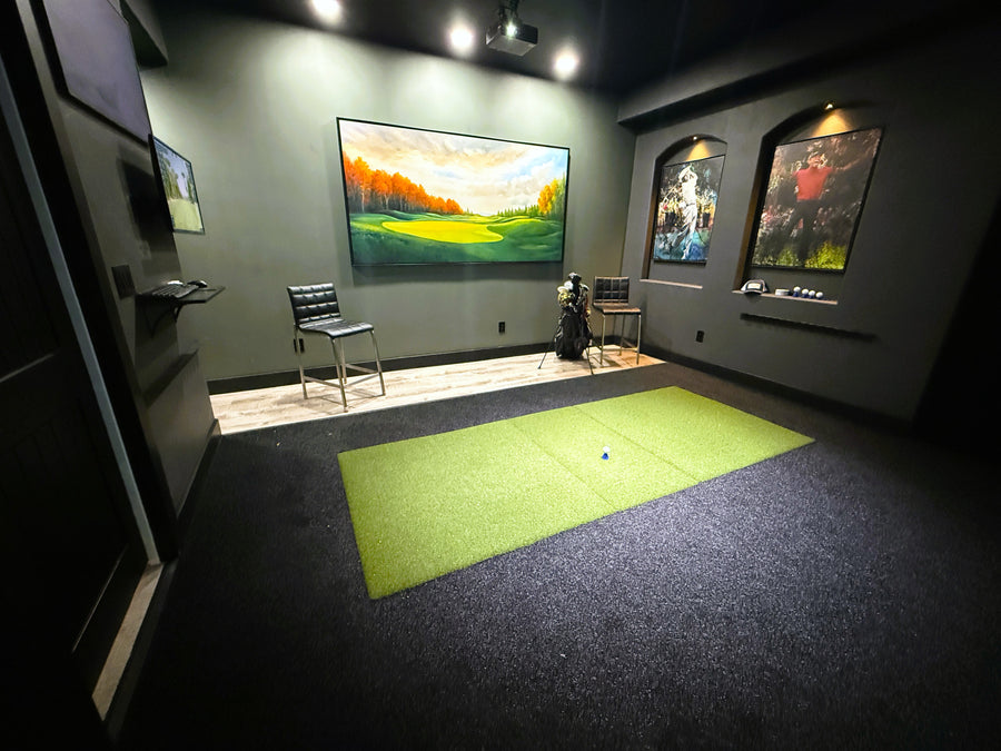 Indoor golf simulator setup with a large screen displaying a golf course.