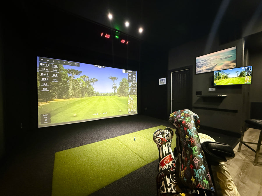 Golf simulator setup in a room with multiple screens and golf equipment.