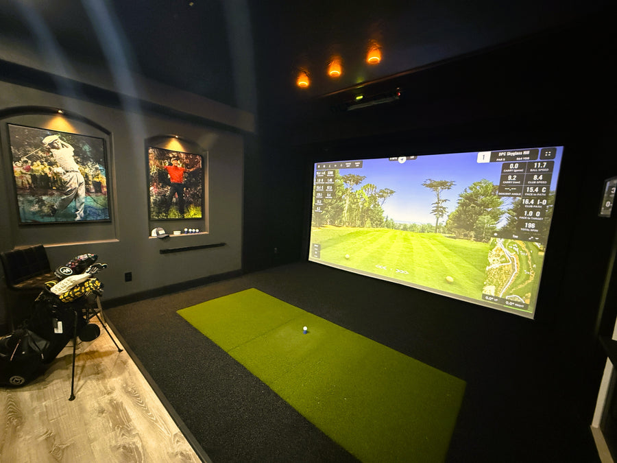 Indoor golf simulator setup with a large screen displaying a golf course.