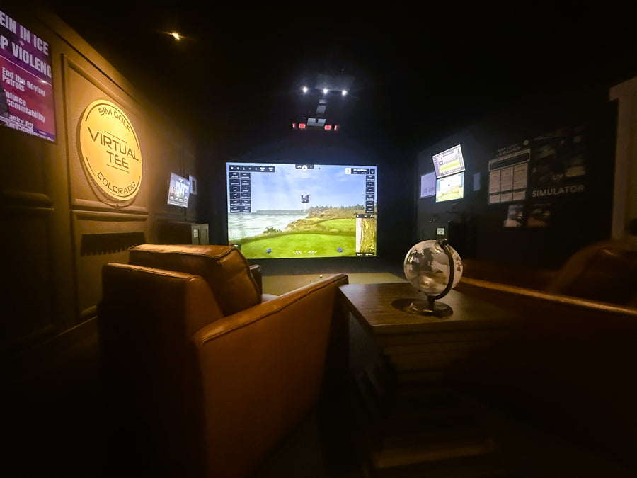 Indoor golf simulator room with a large screen displaying a virtual golf simulation.