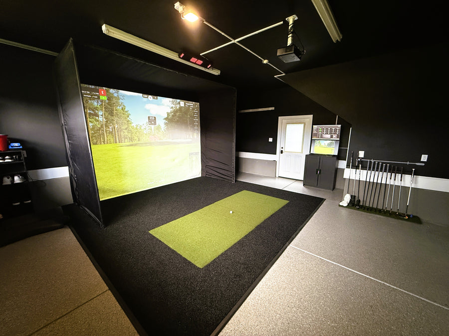 Indoor golf simulator room with screen displaying a golf course.