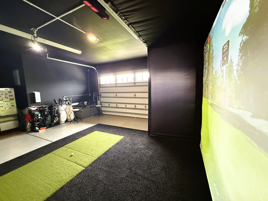 Indoor golf simulator setup in a garage with a screen displaying a golf course.