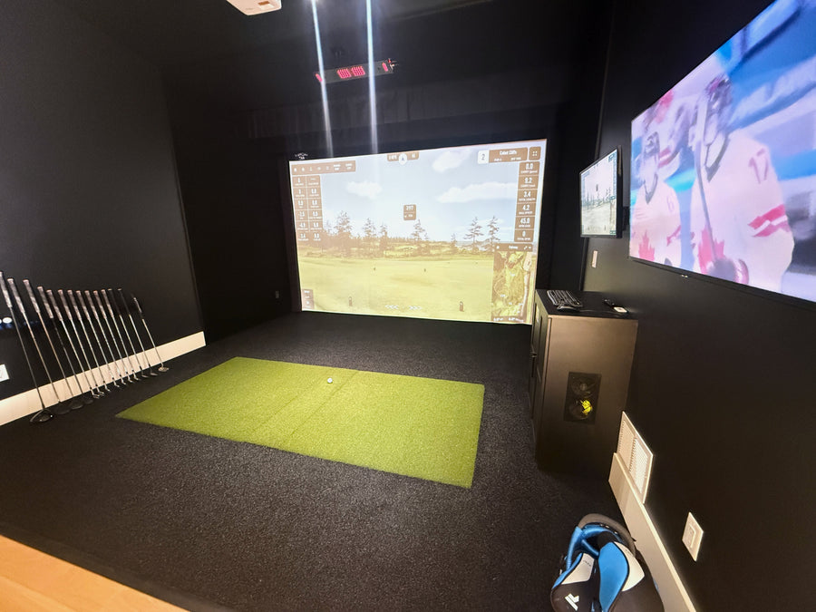 Golf simulator room with screens displaying a golf course and golf clubs on the side.