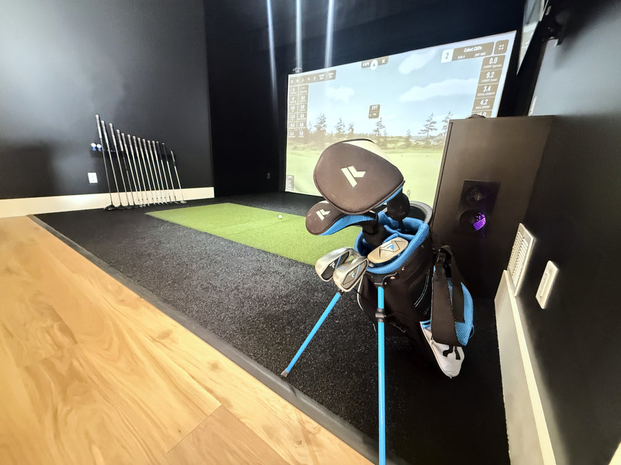 Golf simulator setup with golf clubs and screen displaying a golf course.