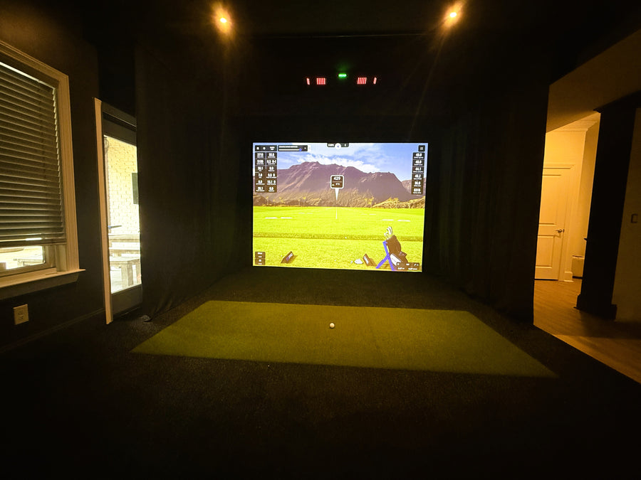 Indoor golf simulator setup with a screen displaying a golf game.