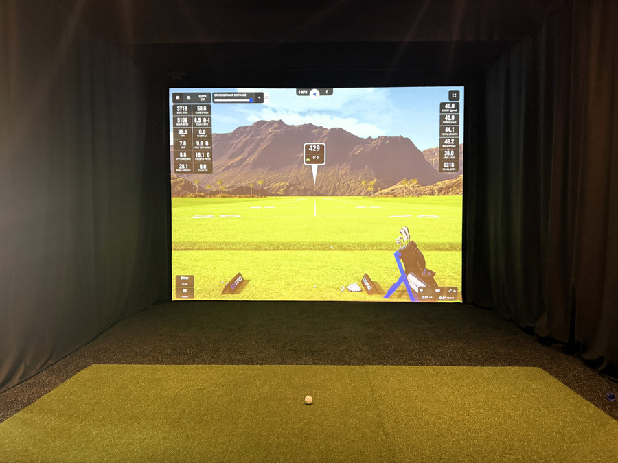 Golf simulator setup with screen displaying a golf course and mountains.