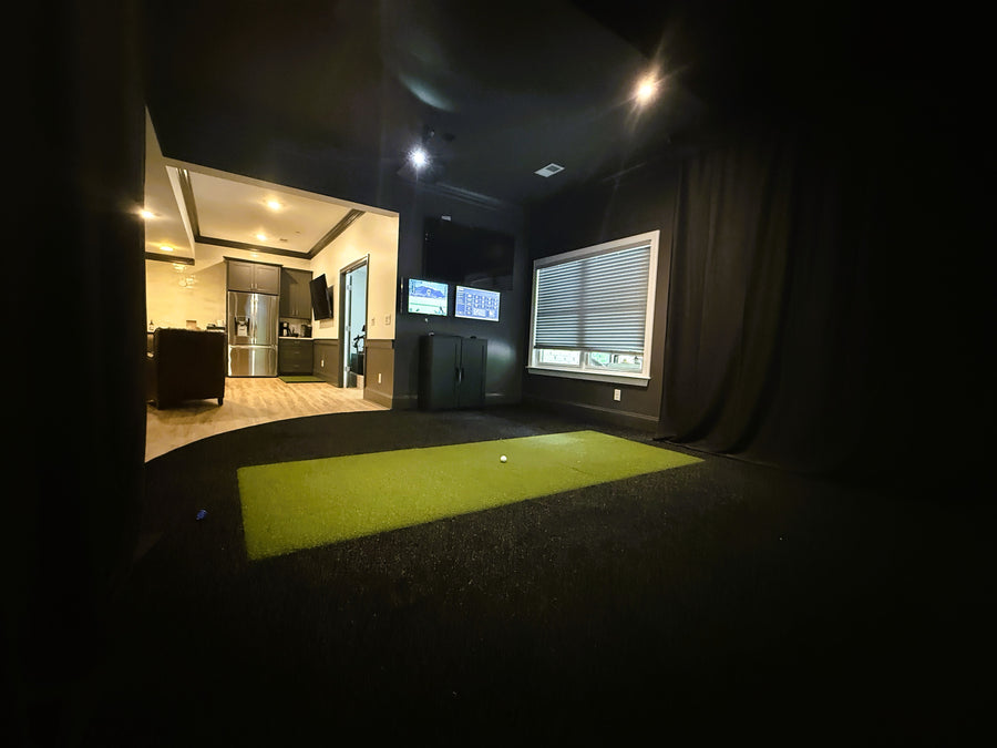 Golf simulator with tv monitors in a darkened room