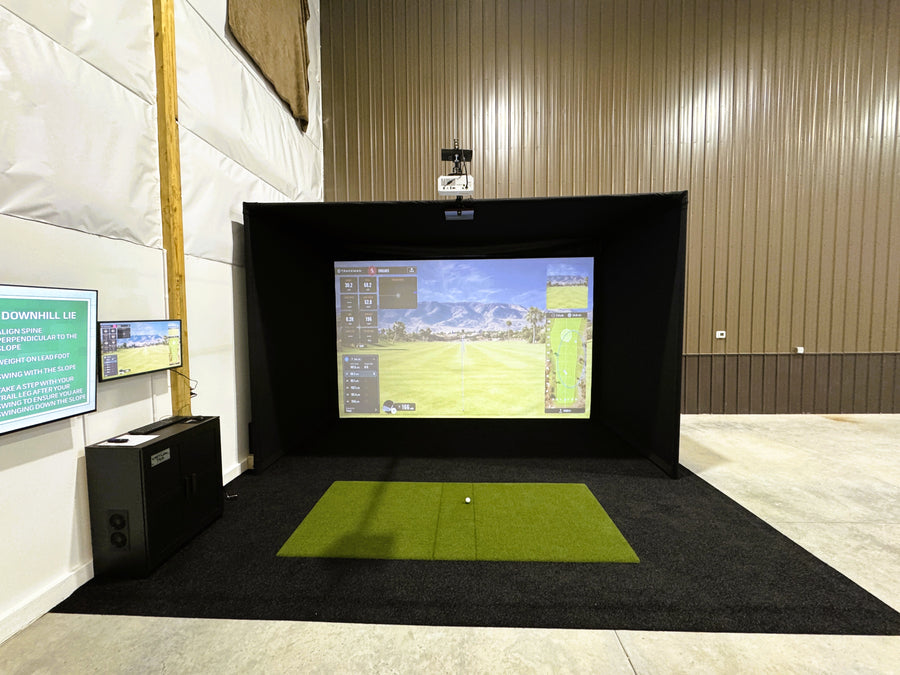 Indoor golf simulator setup with screen displaying a golf course.