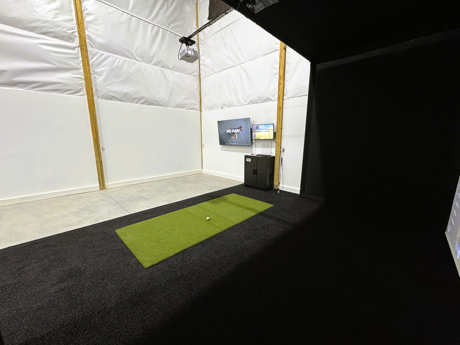 Golf simulator room with green mat and TV on the wall