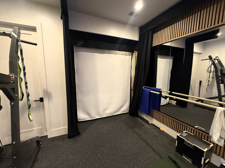 Gym golf simulator room with exercise equipment and a white curtain.