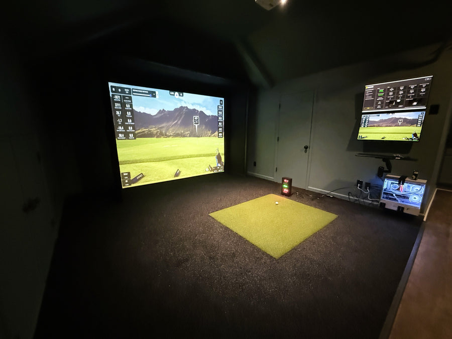 Indoor golf simulator setup with two screens displaying golf environments.