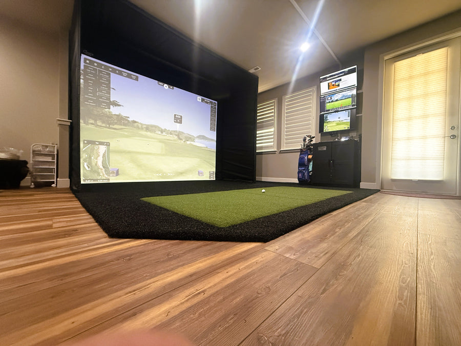 Indoor golf simulator setup with screen displaying a golf course.