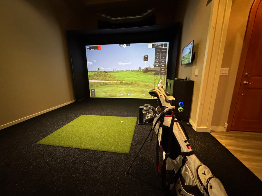Golf simulator setup in a room with a screen displaying a golf course.