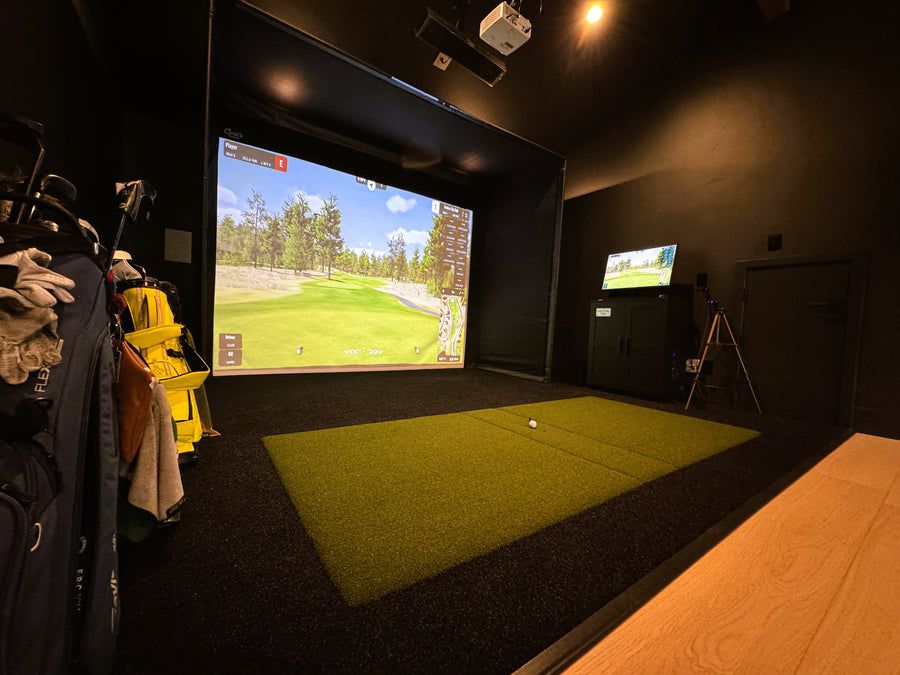 Indoor golf simulator setup with two screens displaying a golf course.