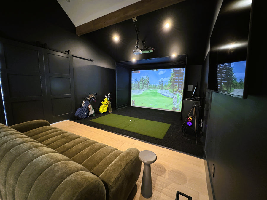 Indoor golf simulator area with a screen displaying a golf simulation game, surrounded by dark walls.