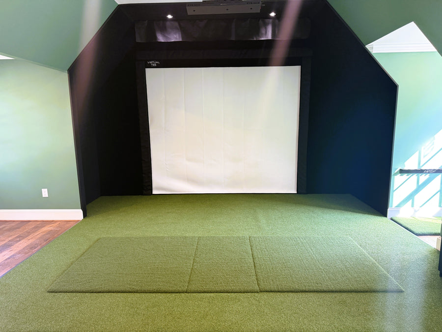 Golf simulator room with green carpet, white screen, and black box on a green wall.