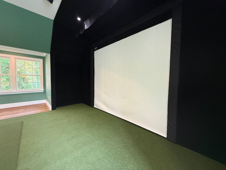 Golf simulator setup with a projector screen and ceiling lights.
