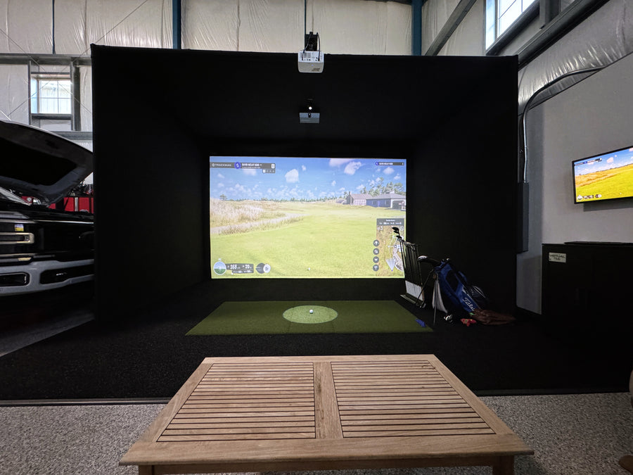Golf simulator setup in a room with a screen displaying a golf course.