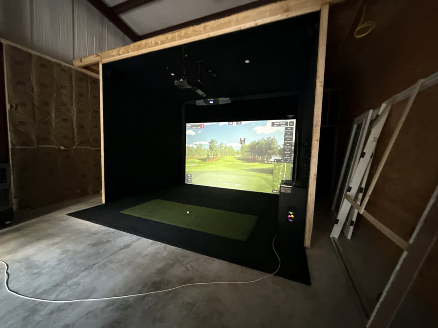 Indoor golf simulator setup with a screen displaying a golf course.