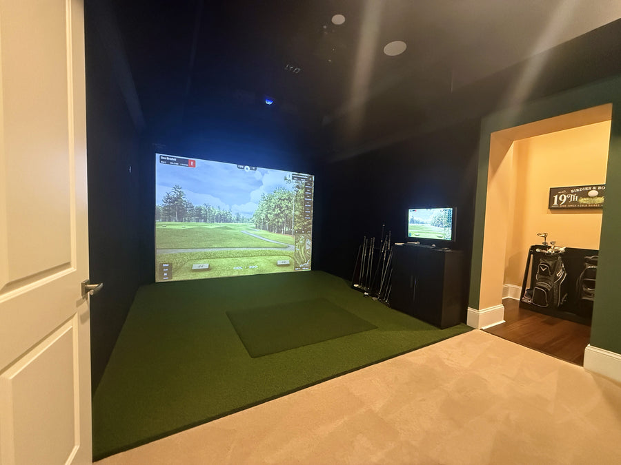 Indoor golf simulator setup with two screens displaying a golf course.