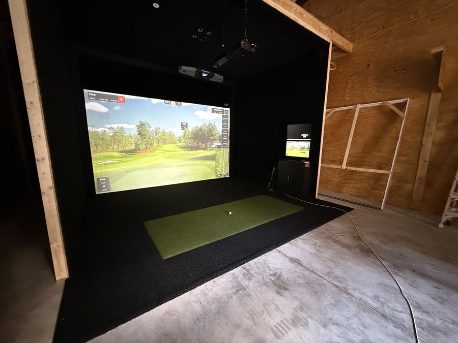 Indoor golf simulator setup with screen displaying a golf course.