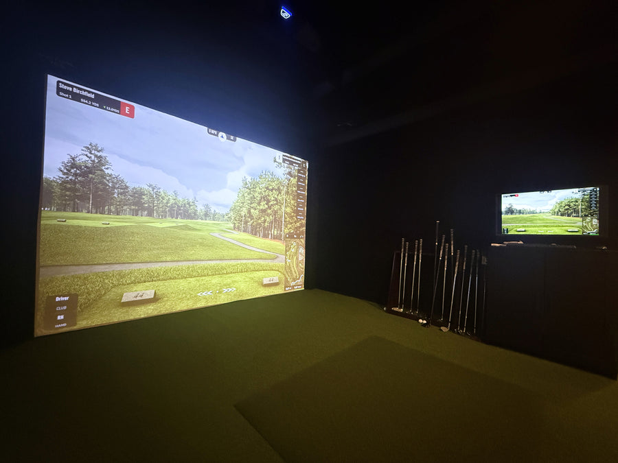 Golf simulator setup with two screens displaying a golf course.