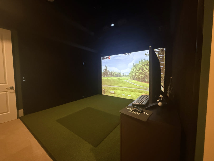 Indoor golf simulator setup with screen displaying a golf course.