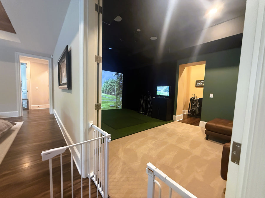Indoor golf simulator setup in a home with a screen displaying a golf course.