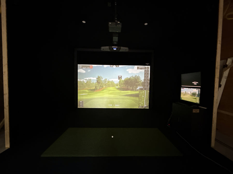 Golf simulator setup with two screens in a dark room