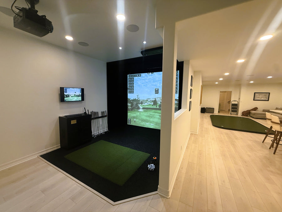 Indoor golf simulator setup in a home entertainment room with a large screen displaying a golf course.