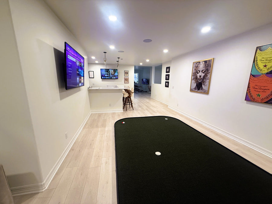 Game room with pool table, wall-mounted TV, and putting green on floor. 