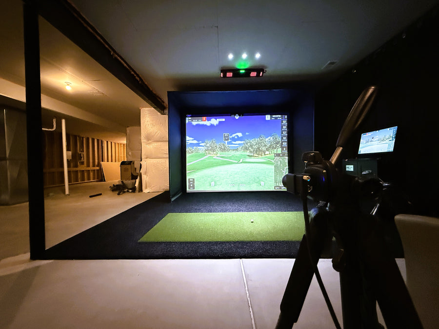 Indoor golf simulator setup with screen displaying a golf course.