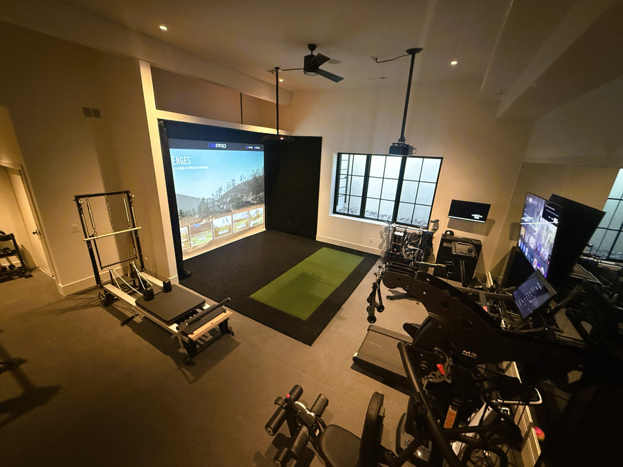 Home gym with exercise equipment and a large golf simulator screen displaying golf course.
