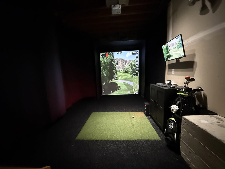 Indoor golf simulator setup with two screens displaying a golf course.