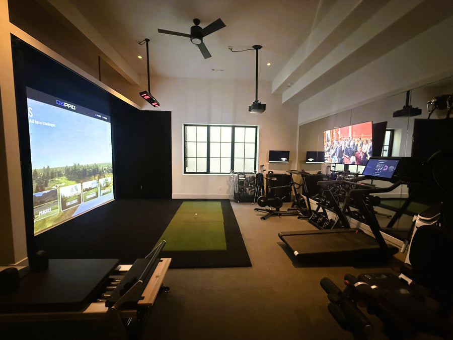 Golf simulator room with gym equipment behind it.