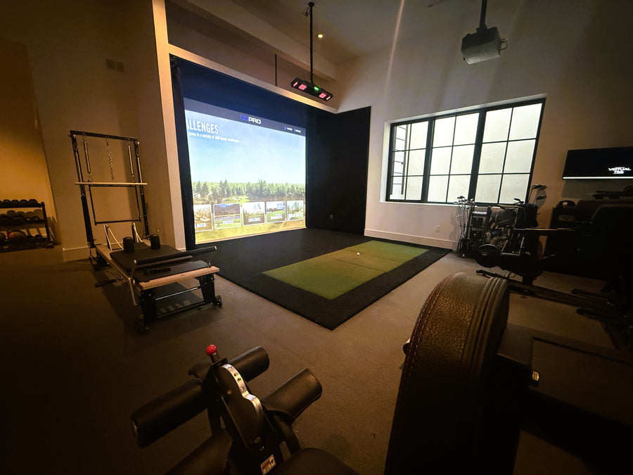 Indoor golf simulator setup with a large screen displaying a golf course.