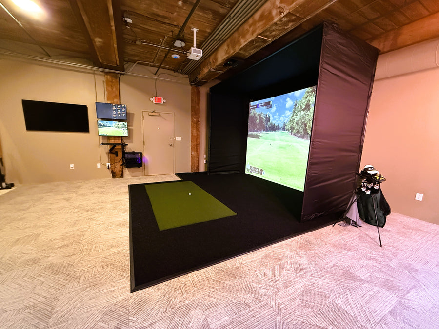 Golf simulator setup in a room with multiple screens displaying golf game graphics.