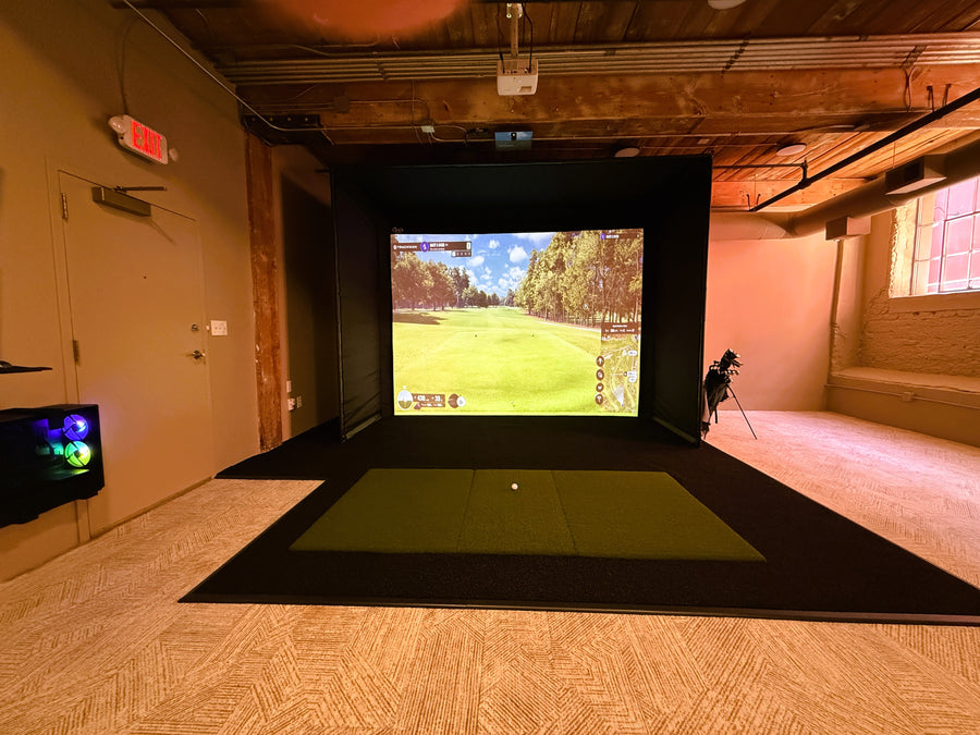 Indoor golf simulator setup with screen displaying a golf course.