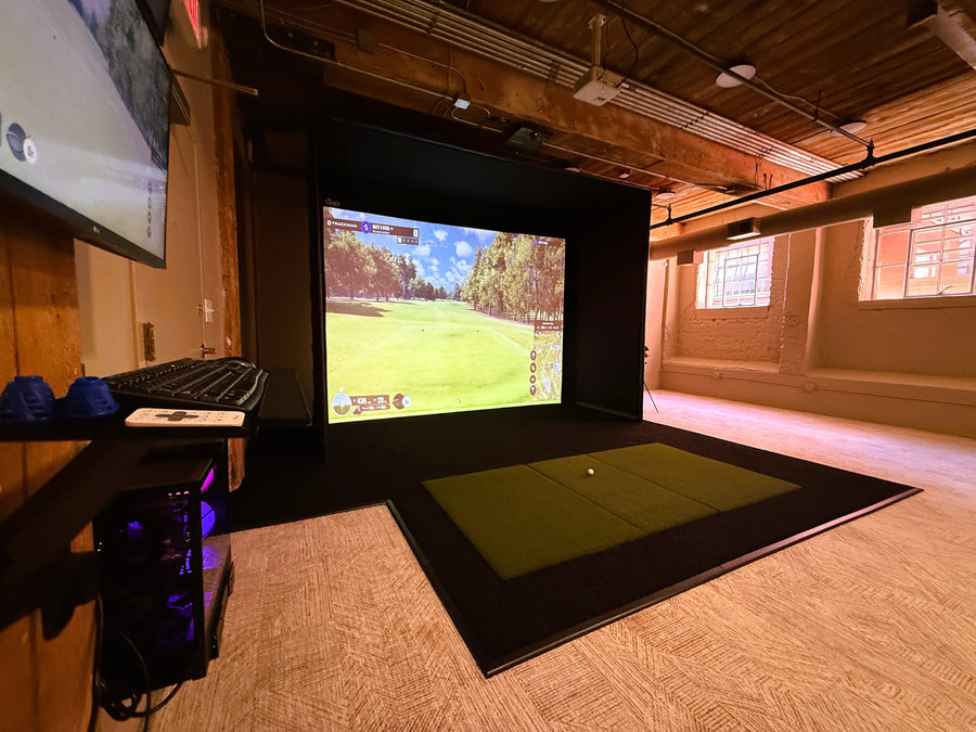 Indoor golf simulator setup with screen displaying a golf course.