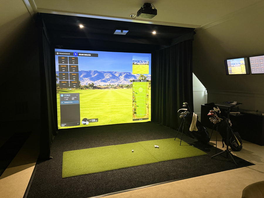Indoor golf simulator setup with large screen displaying a golf course.