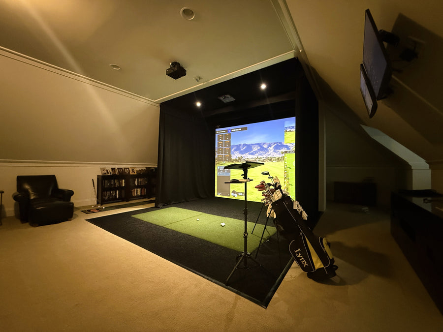 Indoor golf simulator setup in a room with a screen displaying a golf course.