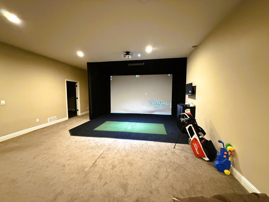 Indoor golf simulator setup in a room with beige walls and carpet.