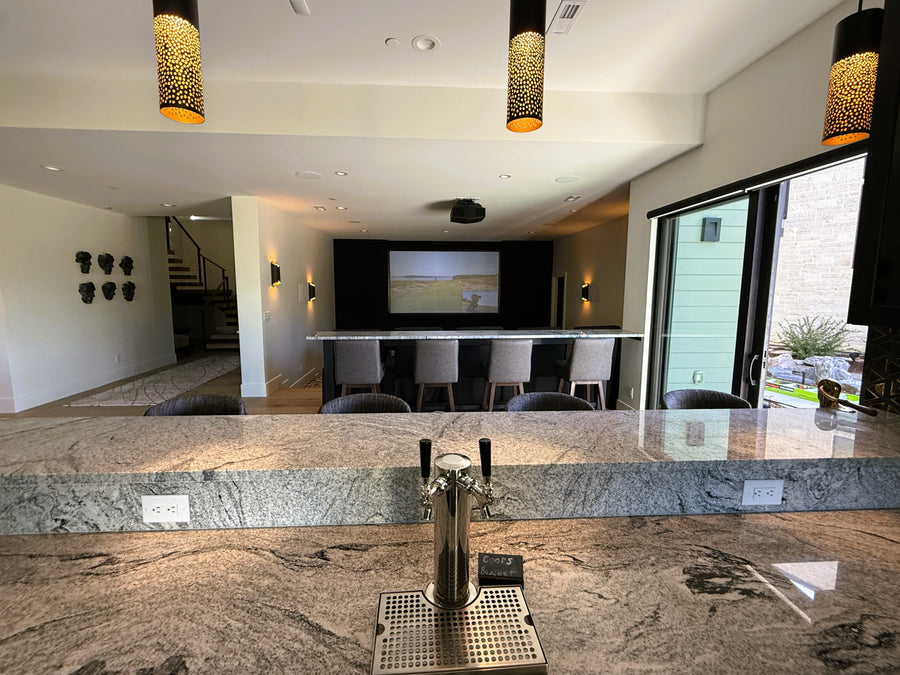Modern kitchen with marble countertop, beer tap, and large screen TV.