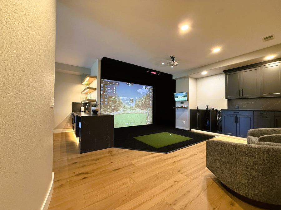 Modern home entertainment room with a large screen and a golf simulator.