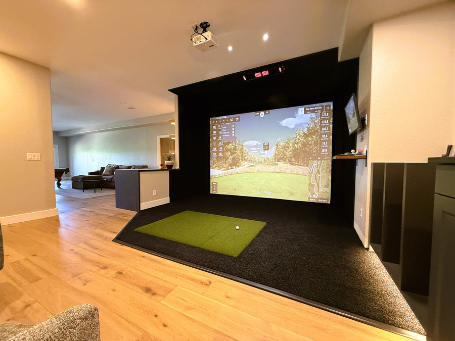Indoor golf simulator setup in a living room with a screen displaying a golf course.