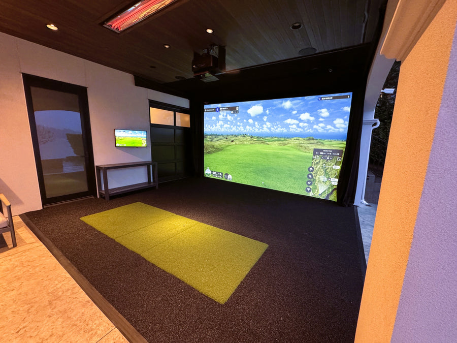 Outdoor patio golf simulator setup with large screen displaying a golf course.