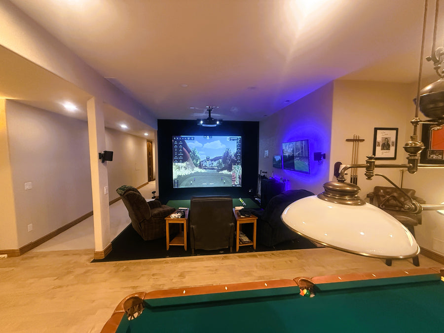 Golf simulator room with pool table, TV, and decorative elements.